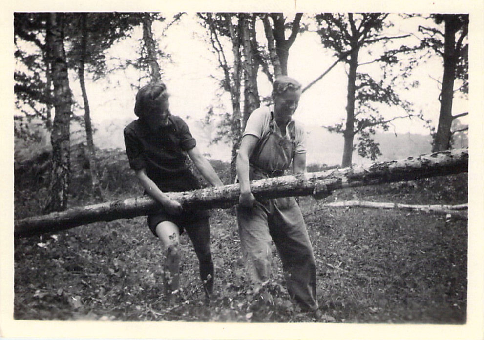 Spenny and another Lumber Jill carrying the trunk of a tree.