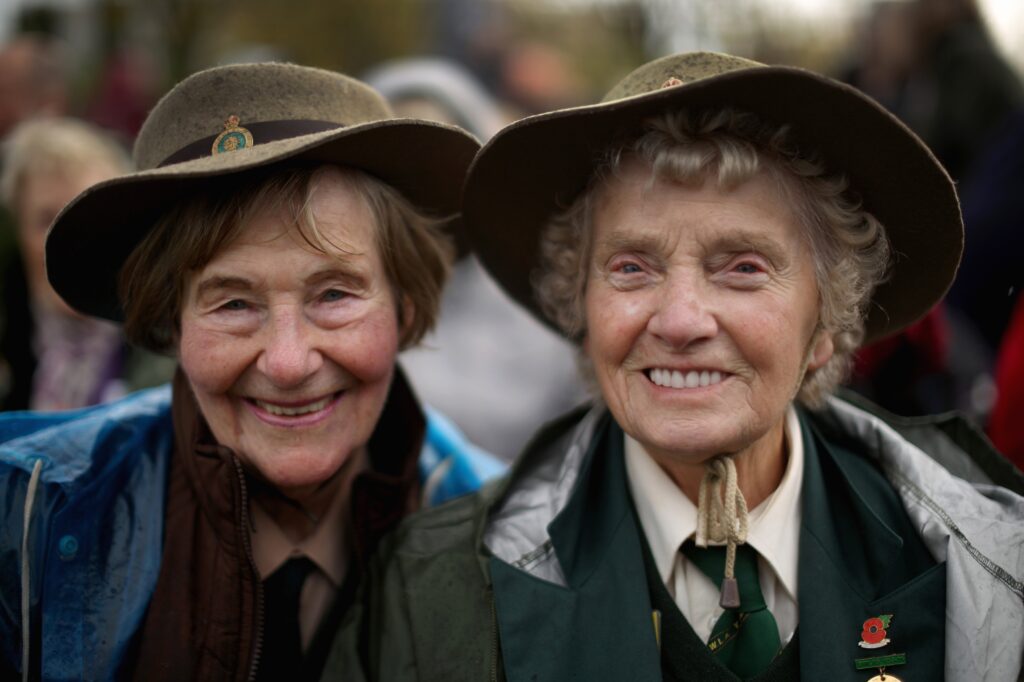 STAFFORD, ENGLAND - OCTOBER 21:  Former Land Girls Iris Halfpenny (L) and Iris Newbould smile as they brave the high winds during the dedication ceremony of the new memorial to honour women who served in the Land Army during World War Two at The National Memorial Arboretum on October 21, 2014 in Stafford, England. The new bronze memorial, depicting a Land Girl and Lumber Jill was unveiled by Sophie, Countess of Wessex, with the ceremony being attended by more than 400 former Land Army girls.  (Photo by Christopher Furlong/Getty Images)