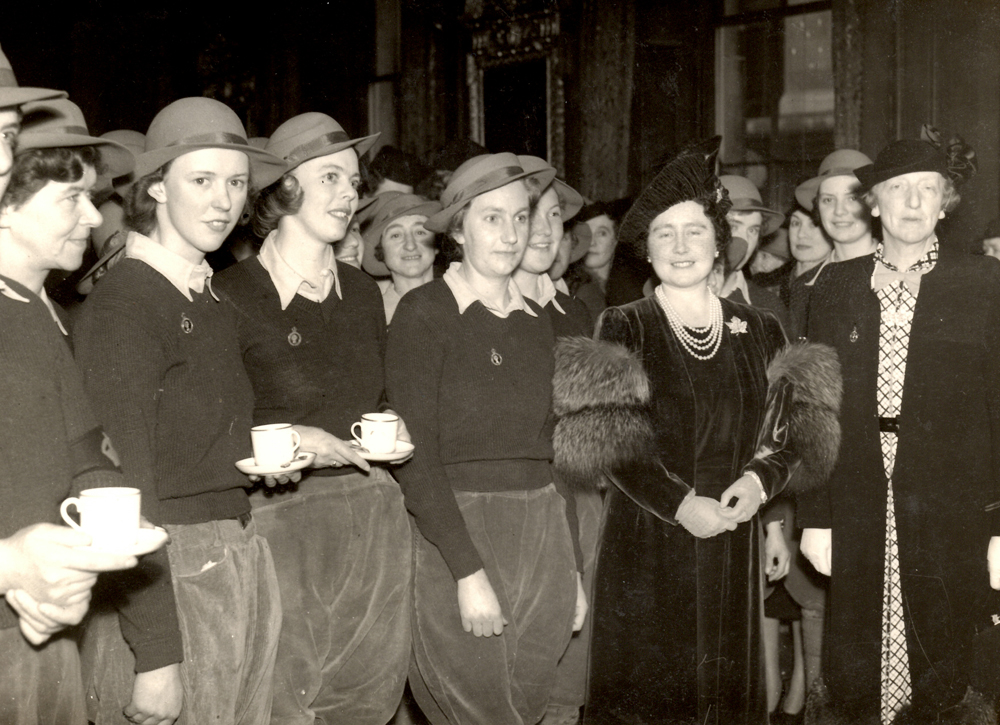 Land Girls standing next to Queen Elizabeth (later Queenmother) and Lady Gertrude Denman at Goldsmiths' Hall.