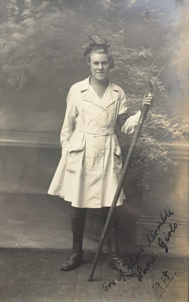 A First World War Land Girl holding a pitchfork.