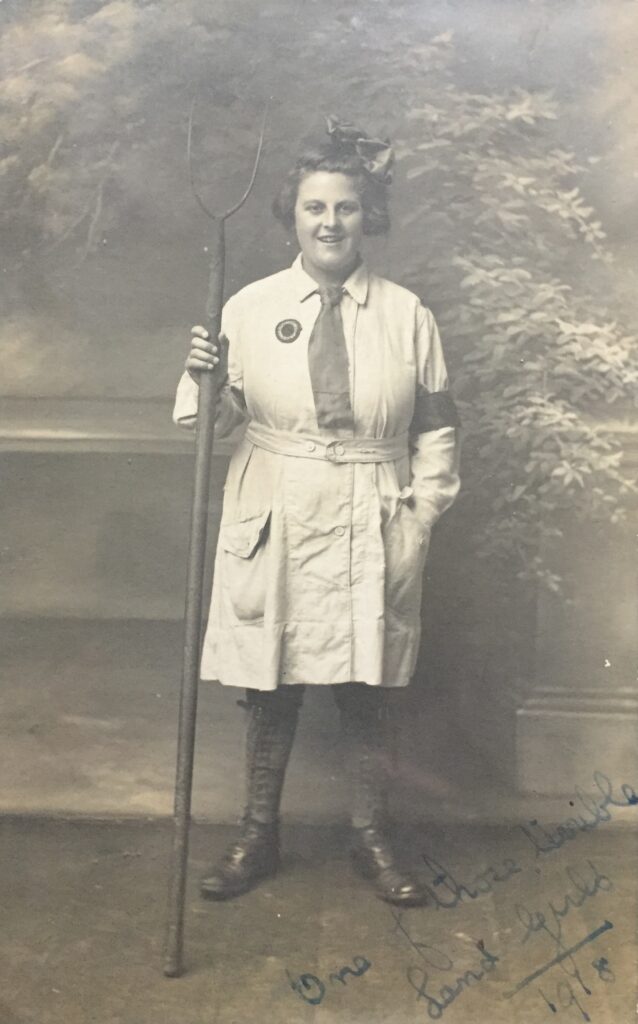 A First World War Land Girl holding a pitchfork.